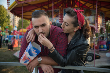 young cute  couple in amusement  park eating pop corns 