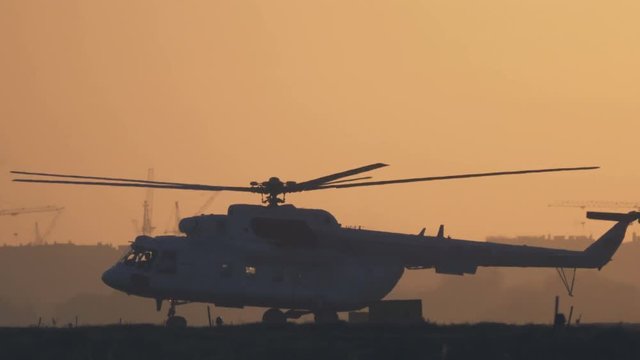 Helicopter is taxiing on the airfield and  takeoff at sunset