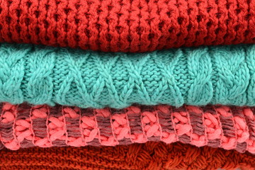 Knitted red, orange, green scarves. Collection of woolen clothes.