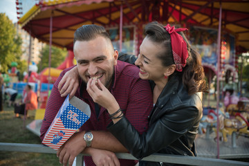 young cute  couple in amusement  park eating pop corns 