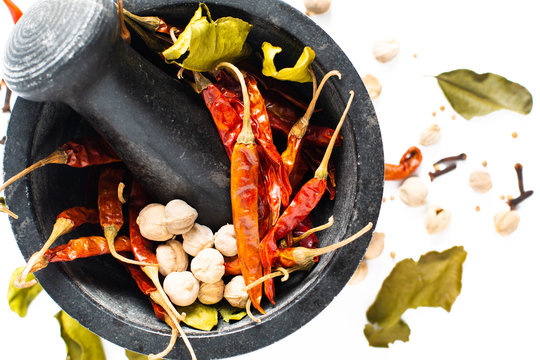 Food concept Exotic Thai dried spices chilies in mortar, Kaffir lime, cloves, thai cardamom white pod and coriander seeds on white background