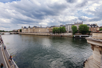 Fototapeta na wymiar Paris, France - August 16, 2017. View of Seine river embankment, Cite island with Conciergerie Palace and Prison from oldest parisian bridge Pont Neuf.