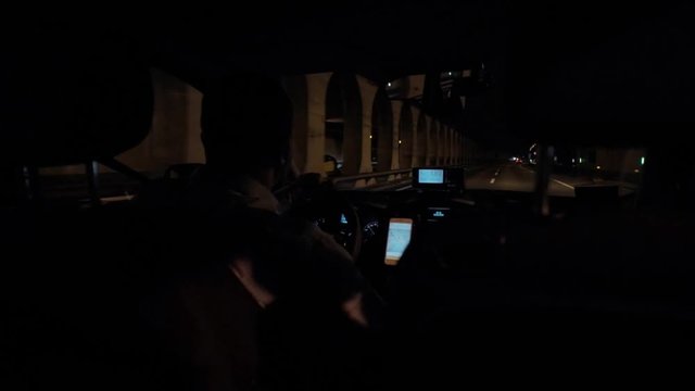 Night time shot from back seat of cab on highway and empty street with lights,taxi driver or sharing economy app user drives passenger to location, businness hotel or airport shuttle,gps on smartphone