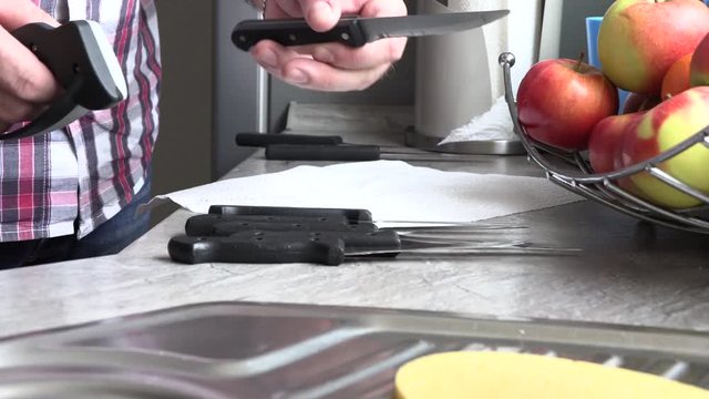 The man is sharpening a kitchen knife