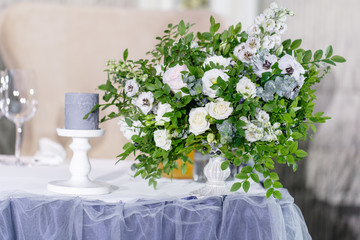 Beautiful and exquisite decoration of the wedding celebration. Banquet served table with a blue tablecloth, plates and candlesticks with candles.