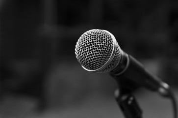 Black and white image of microphone with blured in background.