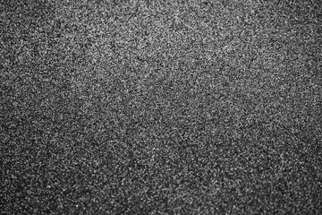 Dark gray background or texture of digital noise or grain of asphalt, graphite.