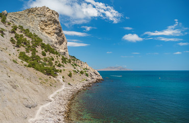 Fototapeta premium Blue sea with the rocky shore in the sunny afternoon