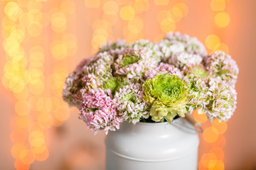 Pink persian buttercup flowers. Curly peony ranunculus in Metallic gray vintage can. Vase with beautiful bouquet on table. Copy space. lights on the background