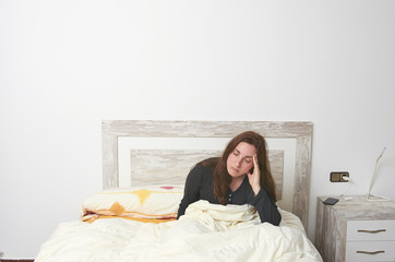 Obraz premium Woman sitting on bed irritated when they hear the alarm clock. Early wake up not getting enough sleep.