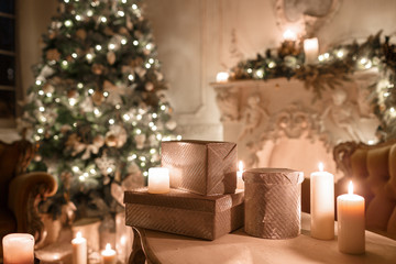 Christmas tree, garlands, candles,lanterns, gifts in the evening. classical interior of a white room with a decorated fireplace, sofa,