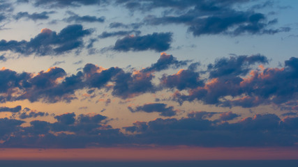 The clouds in the sky are colored by the sun at dawn.