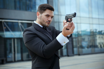 A dangerous man in a suit is aiming from a gun.