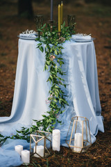 Decorated table with blue tablecloth, herbs, candles, Cutlery in anticipation of a romantic date in nature