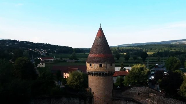 Revealing shot in a small town in France, Cluny, with castle tower, roads, nature sights, hills, and fields.
