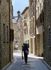 Senderista recorriendo con mochila una calle antigua del pueblo de Benasque (Huesca-Pirineos)