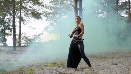 Woman is dancing tribal dance in the pillar of blue smoke