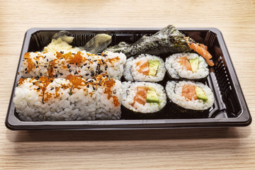 Japanese Cuisine: Tasty Uramaki , Futomaki and temaki served in the take-away box - selective focus