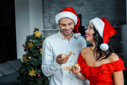 selective focus of young couple in christmas hats eating pizza at home