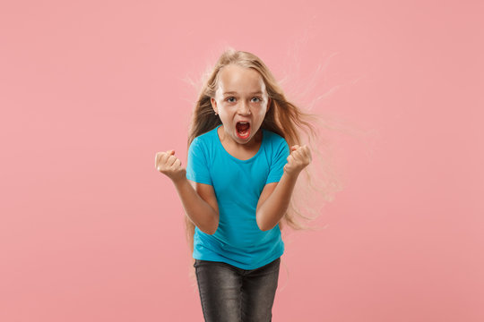 Angry teen girl standing on trendy pink studio background. Female half-length portrait. Human emotions, facial expression concept. Front view.