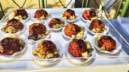 Tray with portions of rice-stuffed tomatoes and roast potatoes - selective focus