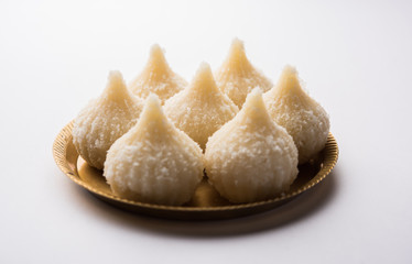Sweet Modak made using coconut, khoya and sugar. Popular Maharashtrian recipe offered to lord Ganesha in Ganesh Festival. Served in a plate. Selective focus