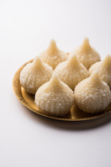 Fototapeta na wymiar Sweet Modak made using coconut, khoya and sugar. Popular Maharashtrian recipe offered to lord Ganesha in Ganesh Festival. Served in a plate. Selective focus