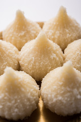 Sweet Modak made using coconut, khoya and sugar. Popular Maharashtrian recipe offered to lord Ganesha in Ganesh Festival. Served in a plate. Selective focus