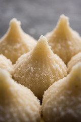 Sweet Modak made using coconut, khoya and sugar. Popular Maharashtrian recipe offered to lord Ganesha in Ganesh Festival. Served in a plate. Selective focus