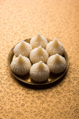 Sweet Modak made using coconut, khoya and sugar. Popular Maharashtrian recipe offered to lord Ganesha in Ganesh Festival. Served in a plate. Selective focus