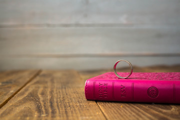 a ring on the bible on wooden background