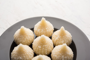 Sweet Modak made using coconut, khoya and sugar. Popular Maharashtrian recipe offered to lord Ganesha in Ganesh Festival. Served in a plate. Selective focus