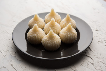 Sweet Modak made using coconut, khoya and sugar. Popular Maharashtrian recipe offered to lord Ganesha in Ganesh Festival. Served in a plate. Selective focus