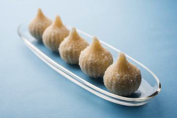 Sweet Modak made using coconut, khoya and sugar. Popular Maharashtrian recipe offered to lord Ganesha in Ganesh Festival. Served in a plate. Selective focus