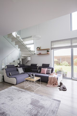 Real photo of a spacious living room interior with a corner sofa, coffee table and carpet