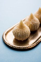 Sweet Modak made using coconut, khoya and sugar. Popular Maharashtrian recipe offered to lord Ganesha in Ganesh Festival. Served in a plate. Selective focus