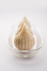 Sweet Modak made using coconut, khoya and sugar. Popular Maharashtrian recipe offered to lord Ganesha in Ganesh Festival. Served in a plate. Selective focus