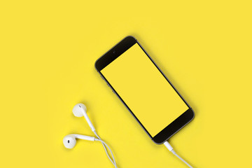 Smart phone and headphone on freesia yellow background