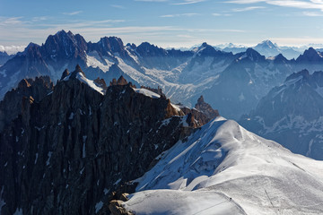 Chamonix, south-east France, Auvergne-Rhône-Alpes. Climbers heading for Mont Blanc. Descending from Aiguille du Midi cable car station towards sunny snow planes and glaciers on border of France