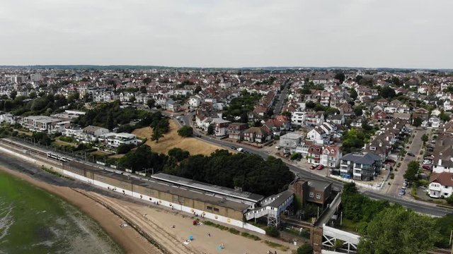 Aerial view of a C2C train just arriving in the Chalkwell Station at noon, the promenade and the sand and mud flats with sea weed when tide is out.