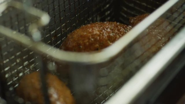 Woman removing food from a deep fryer in a slow motion close up