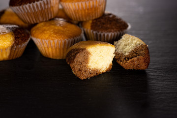 Group of lot of whole two halves of fresh baked marble muffin on grey stone