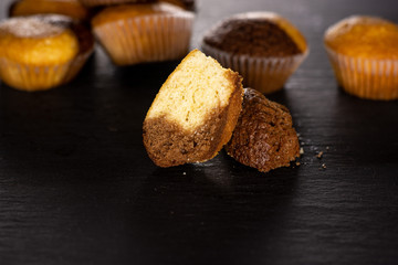 Group of lot of whole two halves of fresh baked marble muffin on grey stone