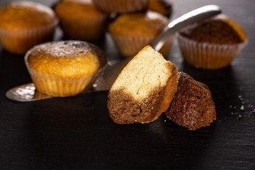 Group of lot of whole two halves of fresh baked marble muffin on silver cake server on grey stone