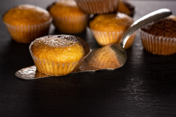 Lot of whole fresh baked marble muffin on silver cake server on grey stone