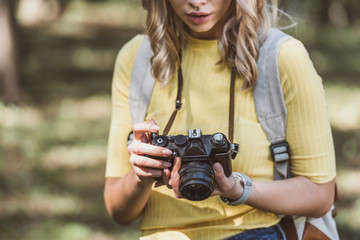 partial view of tourist with photo camera in park