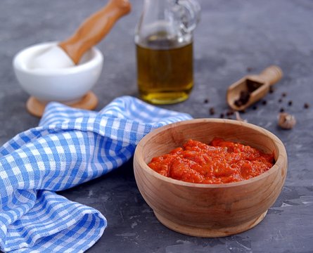 Aivar, vegetable dip or a snack of roasted red sweet peppers and eggplants in a wooden bowl on a dark gray background. Serbian cuisine.