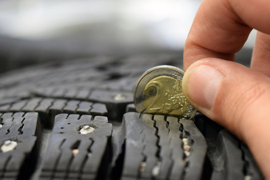 Measuring tire tread depth with two euro coin. Close up image with room for text. Shallow depth of field.