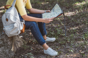 partial view of tourist with backpack and map in park
