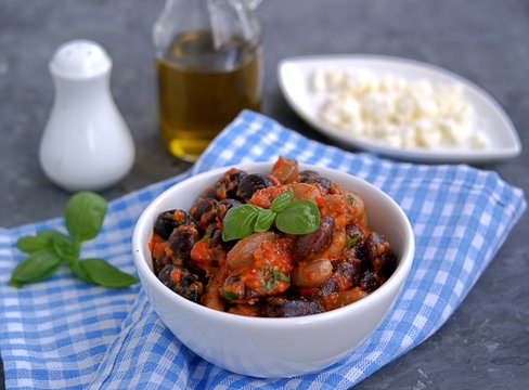 Vegetarian salad of beans with dressing from roasted red pepper, eggplant and olive oil in a white bowl. Served with feta cheese. Hungarian cuisine. Healthy food.